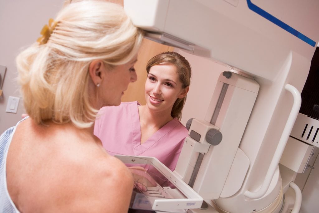 Woman receives mammogram from female nurse.