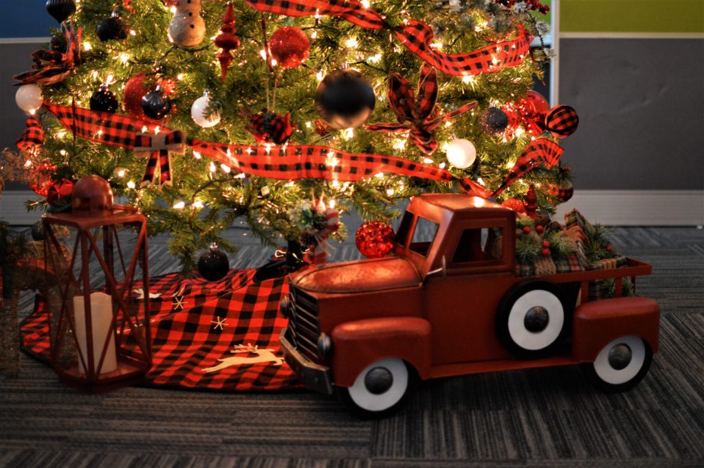 Illustrative image: shows a lit up Christmas tree with a toy truck. 