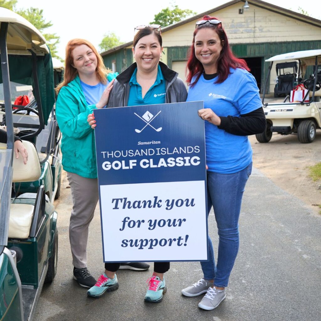 Volunteers at the Thousand Island Golf Classic hold a thank you sign. 