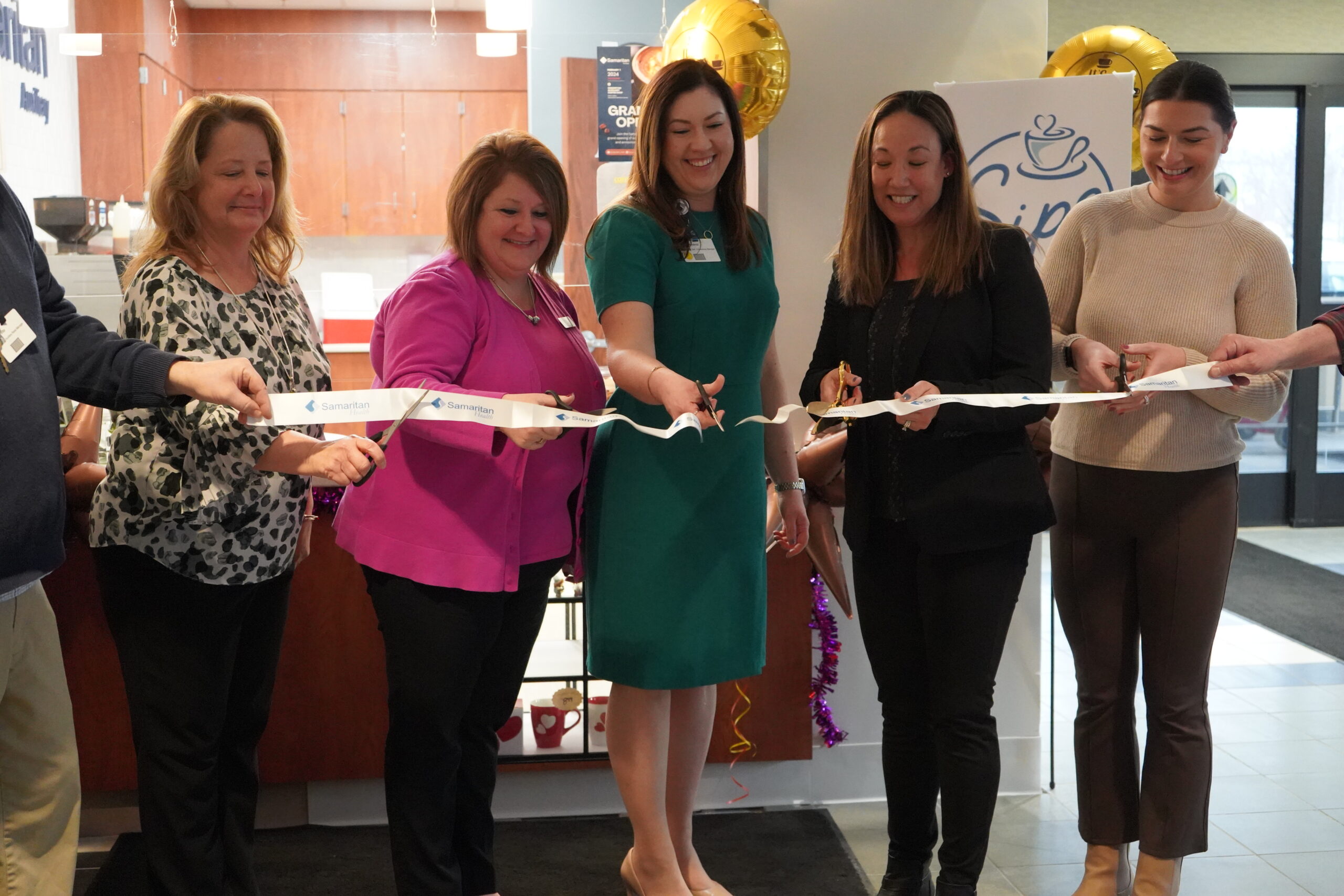 Members of the Samaritan Auxiliary board cut the inaugural ribbon for the new coffee shop: Sips