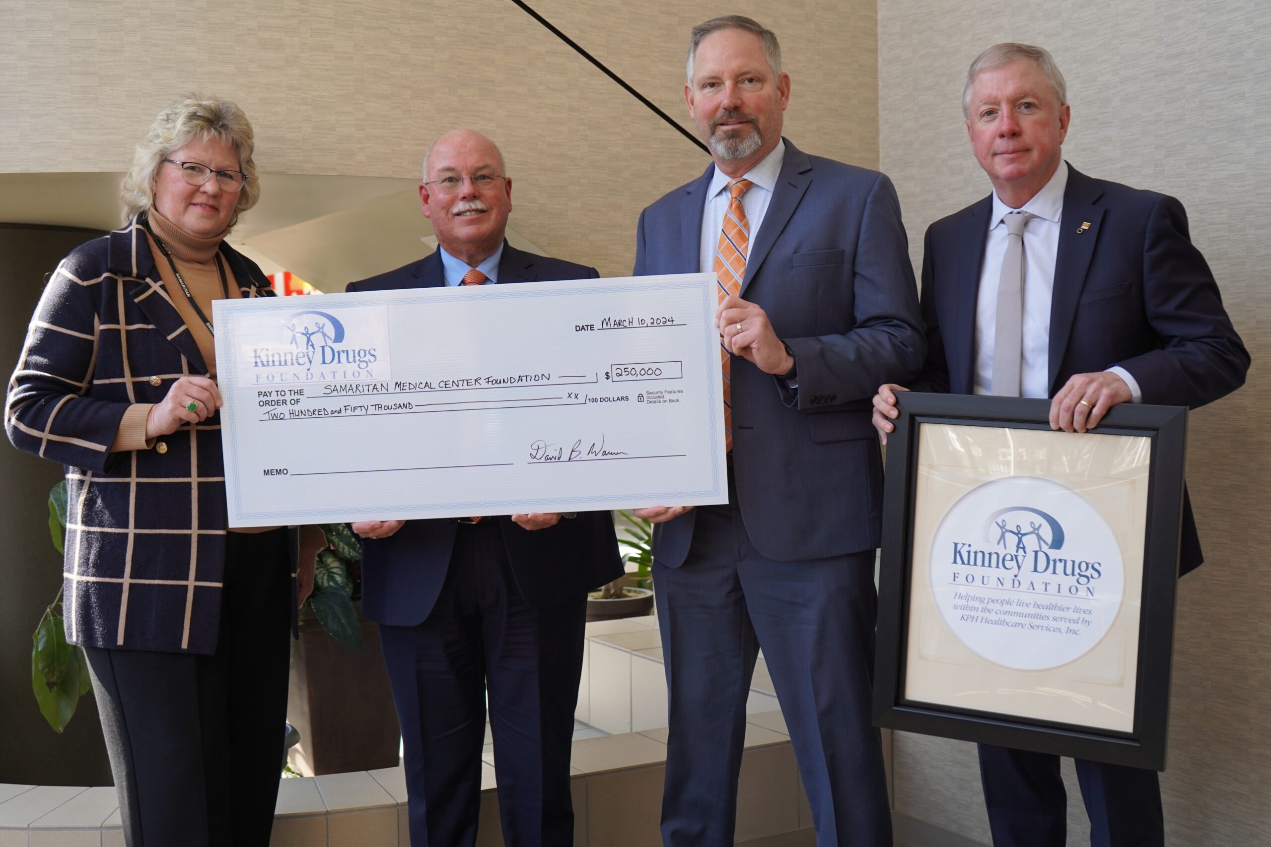 Picture shows Kinney Drugs representatives handing a 250,000 symbolic check to Samaritan Medical Center Foundation representants.