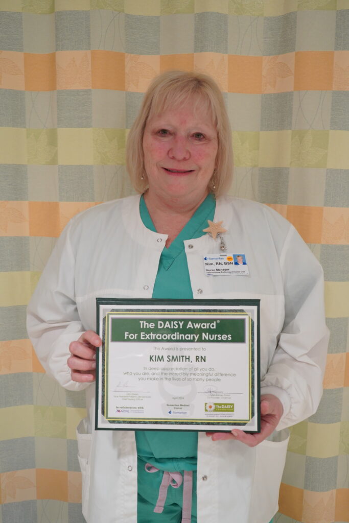 Kim Smith, RN holding her DAISY Award certificate