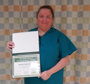 Portrait of Brandi Simpson, Registered Nurse, holding her Daisy Award certificate