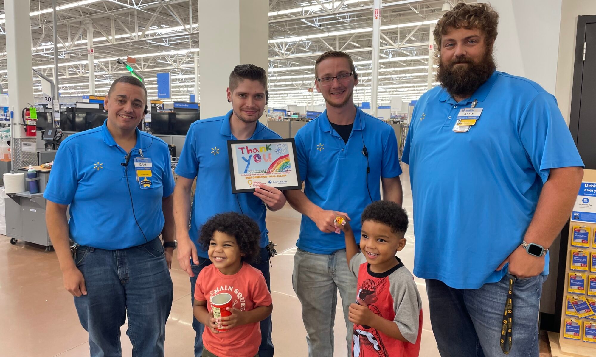 Picture shows Walmart Evans Mills, NY, team members receiving a special art from two CMN of NNY kids.