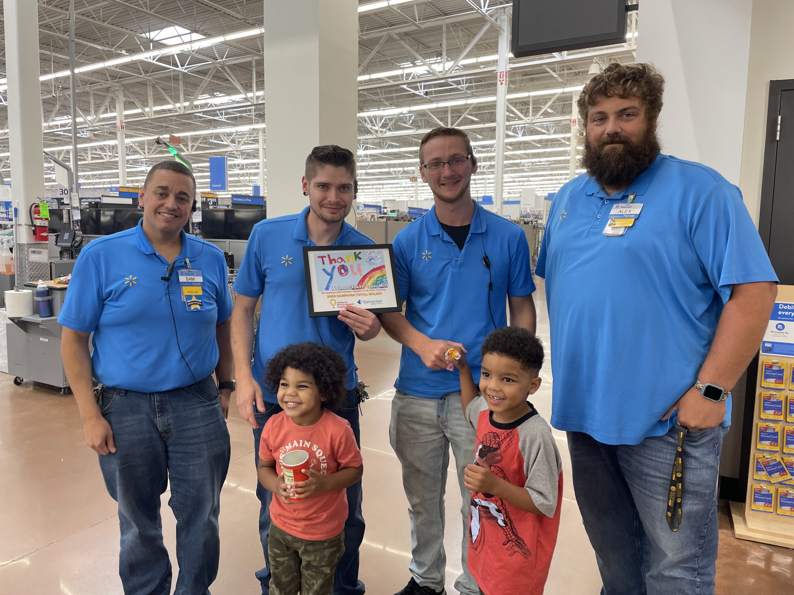 Picture shows Walmart Evans Mills, NY, team members receiving a special art from two CMN of NNY kids.