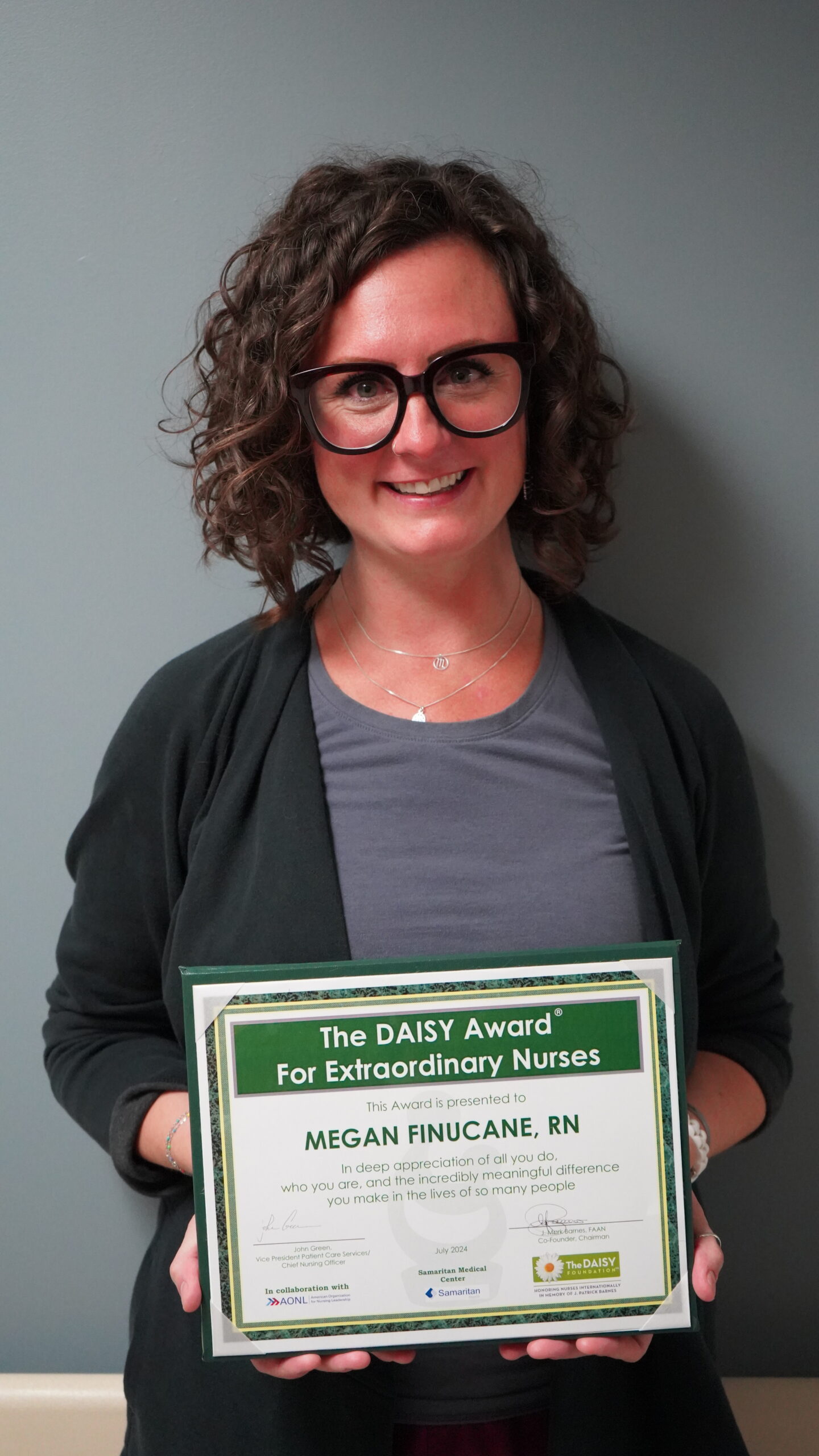 Photo of Megan Finucane, RN, holding her DAISY Award certificate for the month of July 2024