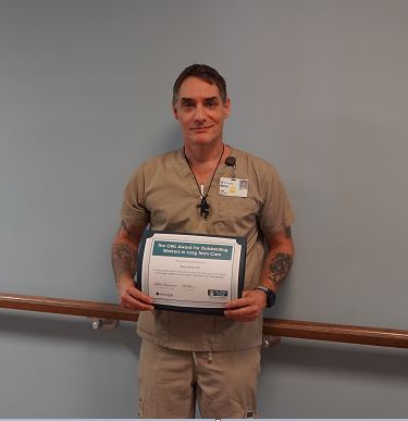 Marco Schmidt, Certified Nursing Assistant, holds his OWL Award certificate.