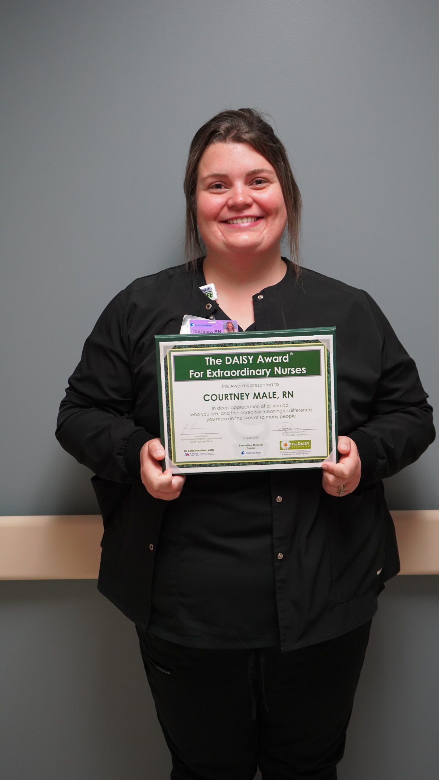 Courtney Male, RN, holding her DAISY Award certificate.