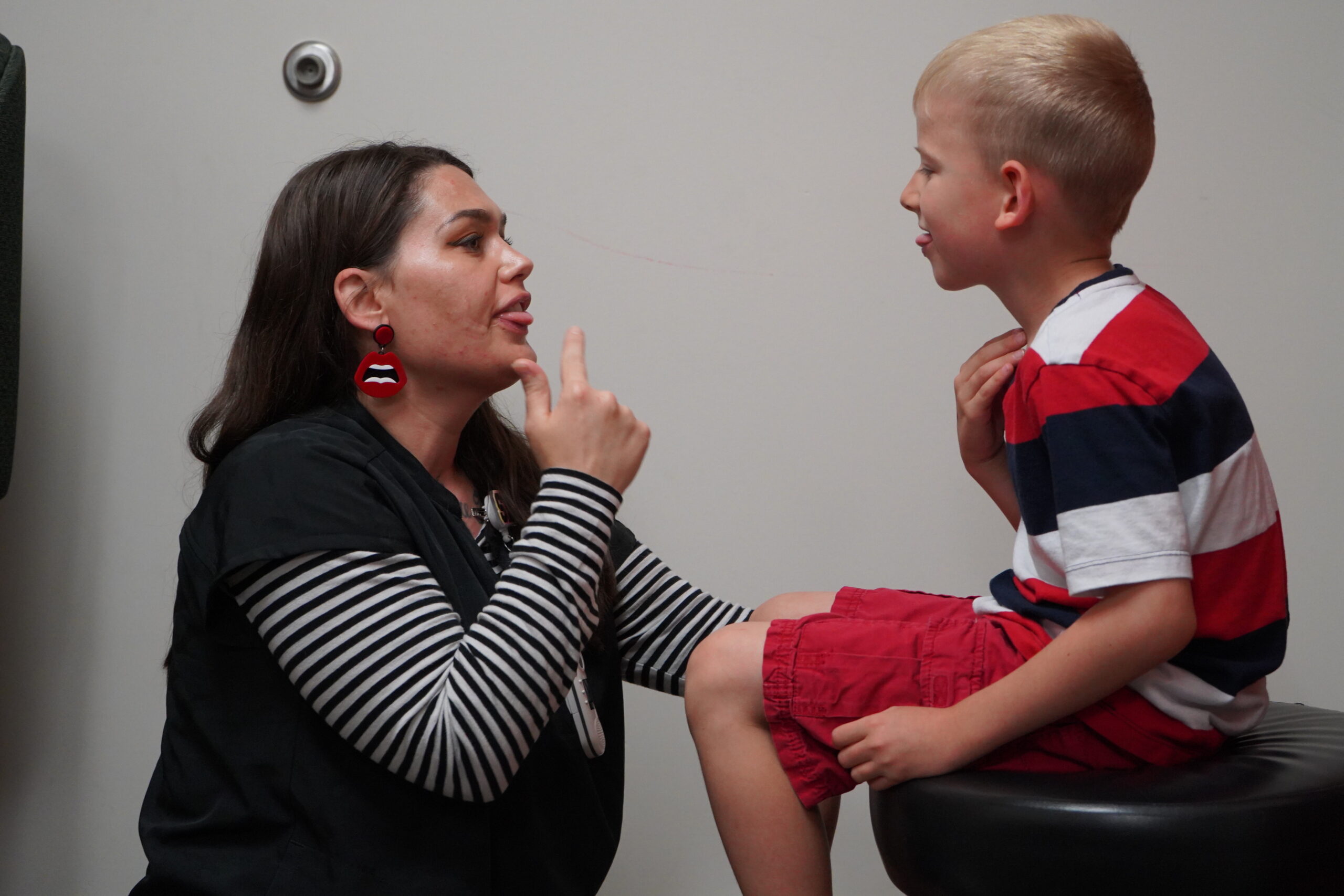 Pediatric speech therapy session: therapist interacts with child.