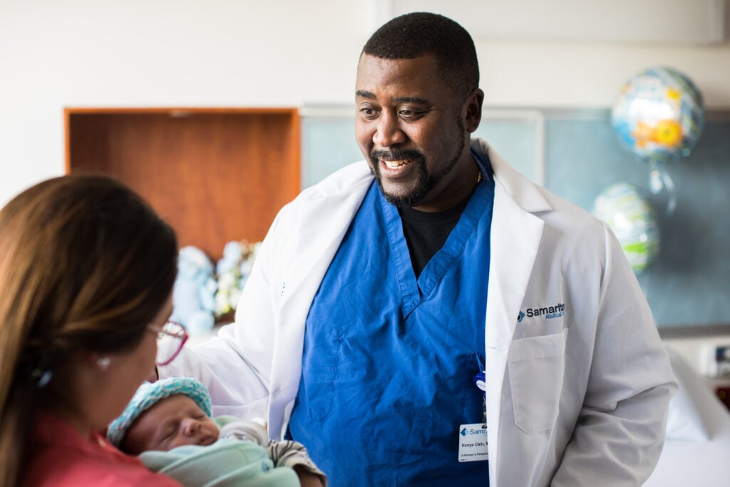 Photo of Dr. Kenya Cain with a baby and a patient at the Car-Freshner Center for Women and Children
