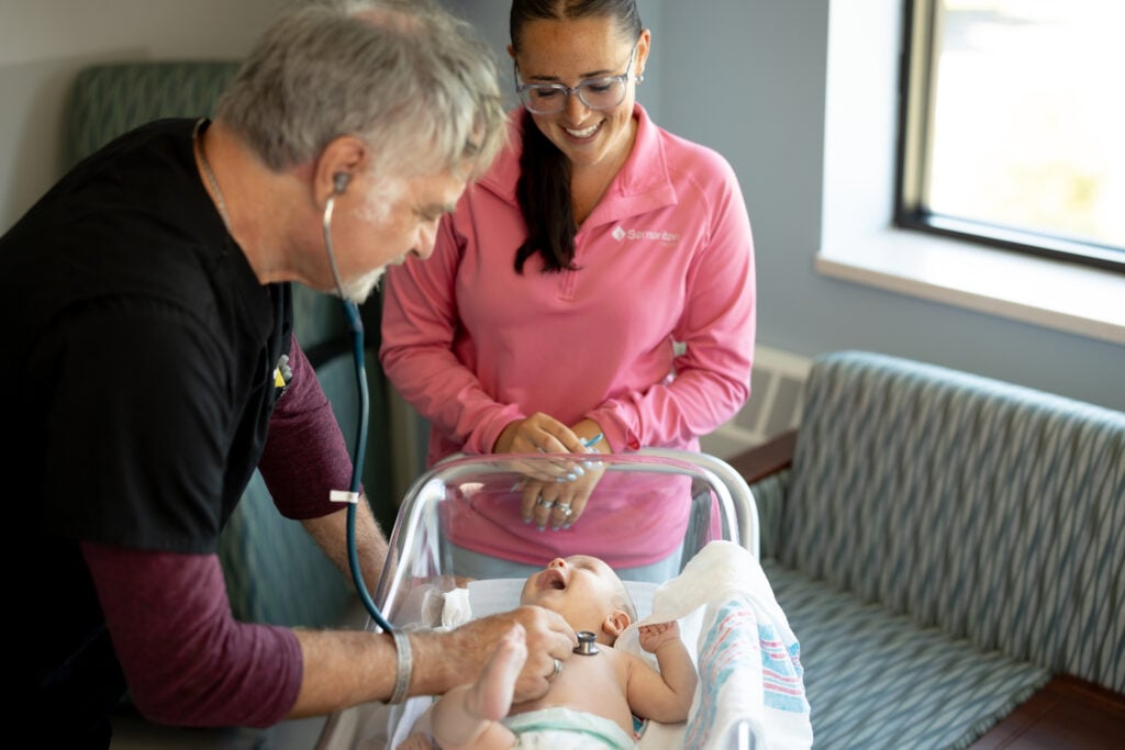 Photo of Dr. Karl Komar ana a nurse checking on baby at the Car-Freshner Center for Women and Children