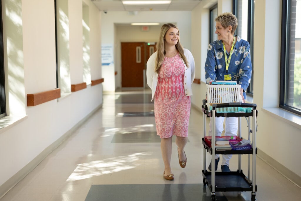 Photo of a female volunteer posing with Volunteer Coordinator Autumn Cooley in the hallway