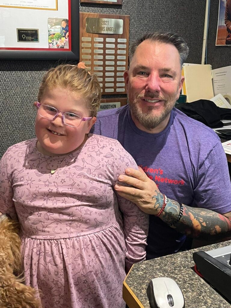 Raelynn Graveline smiles with Johnny Spezzano during the Children's Miracle Network Radiothon