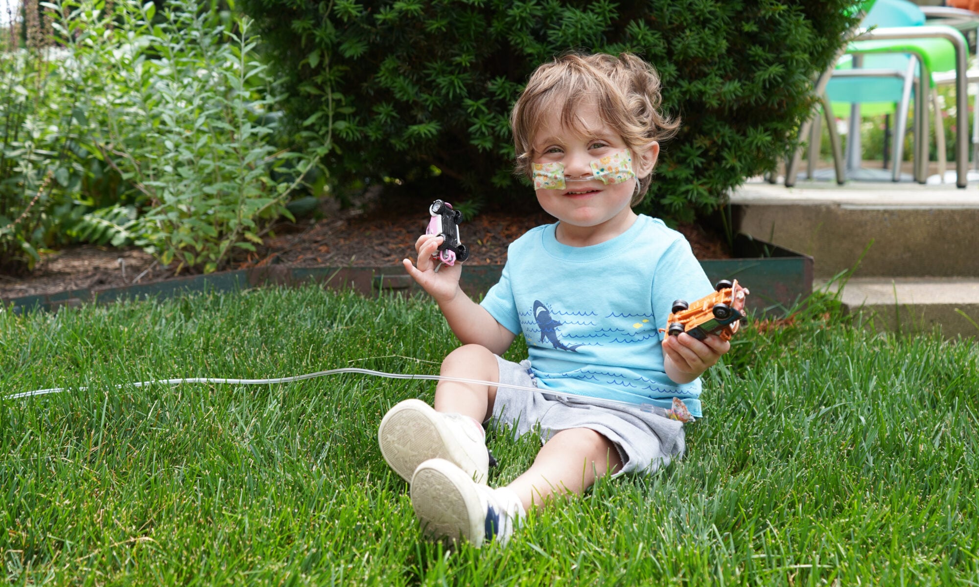 Finley, the 2026 CMN Champion smiles and holds toy cars
