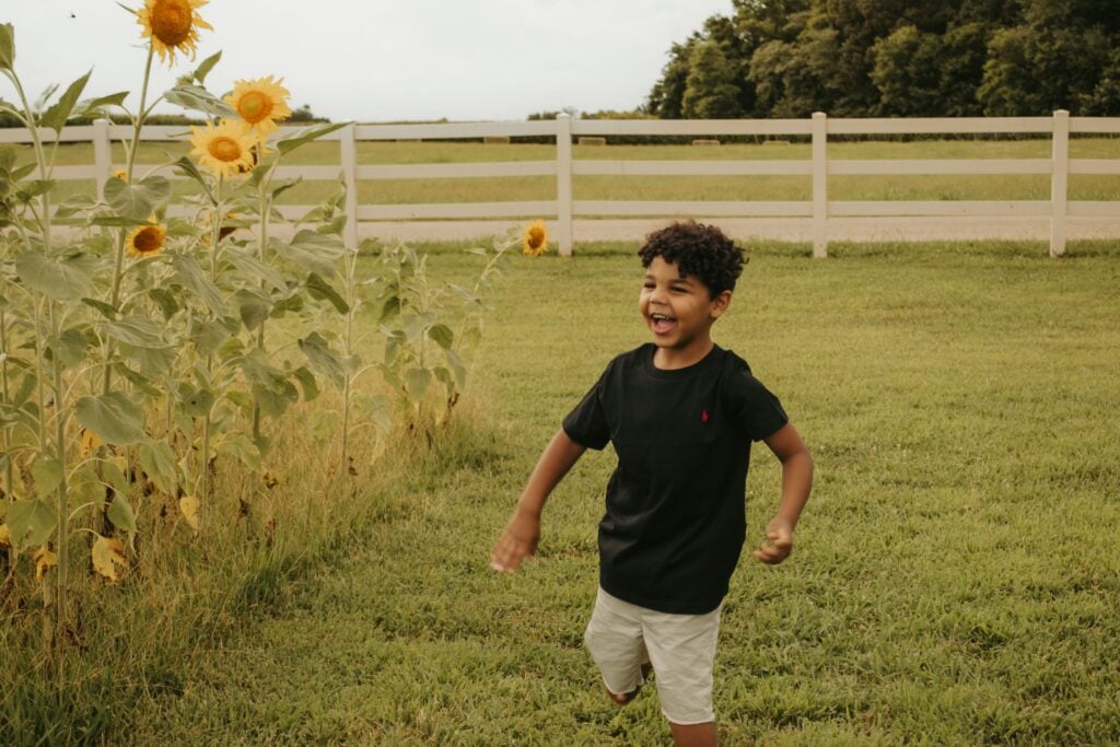 A young boy, Josiah, smiles in a sunflower field