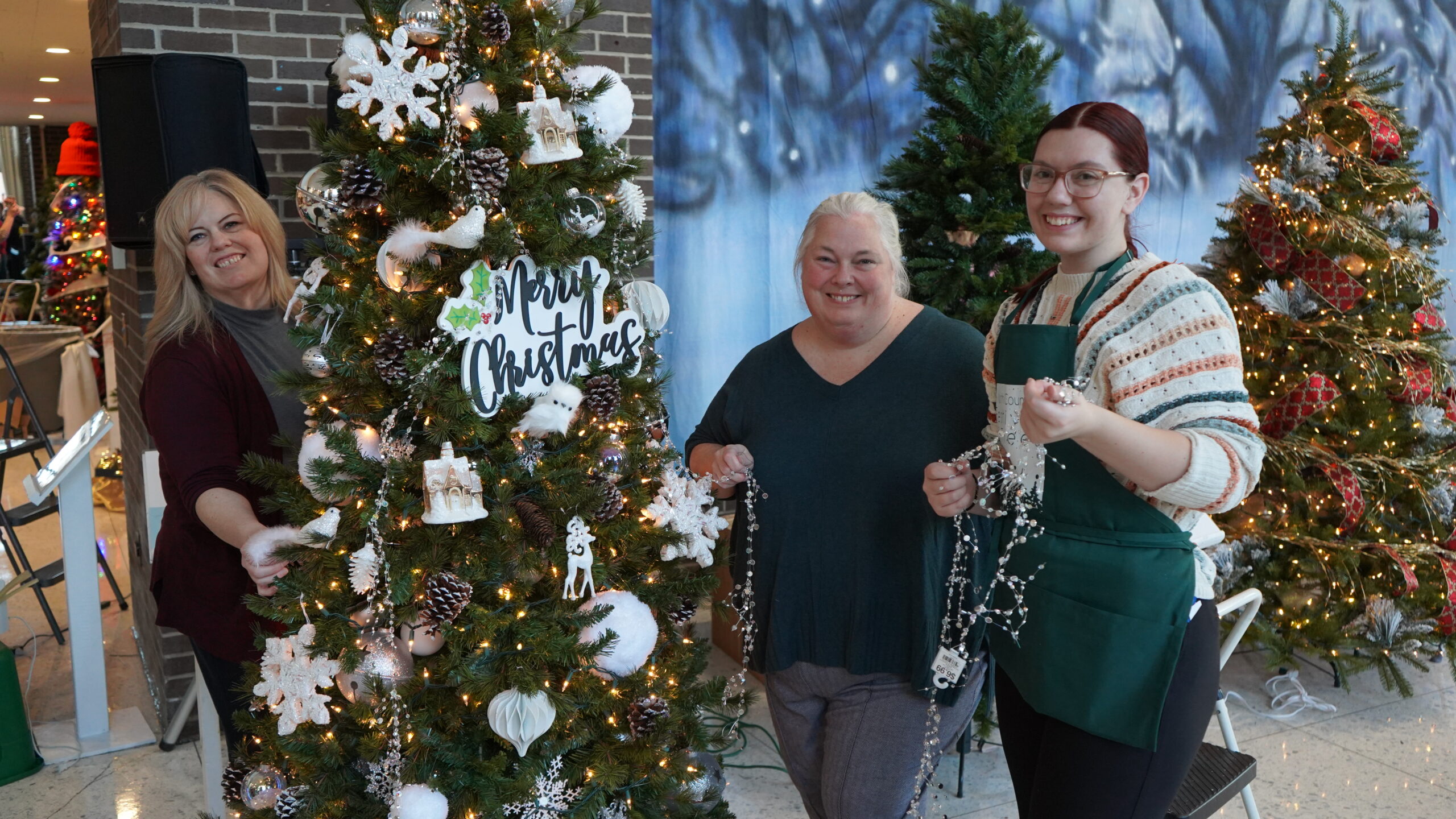 three women decorate a Christmas tree at A North Country Festival of Trees